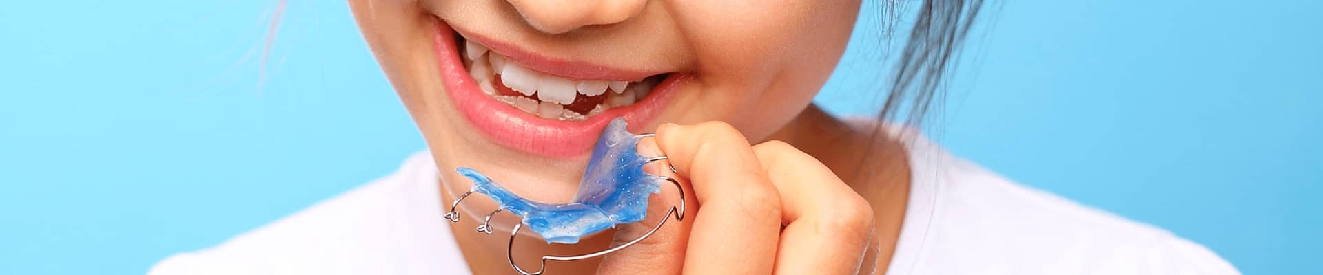 young girl putting on blue dental braces